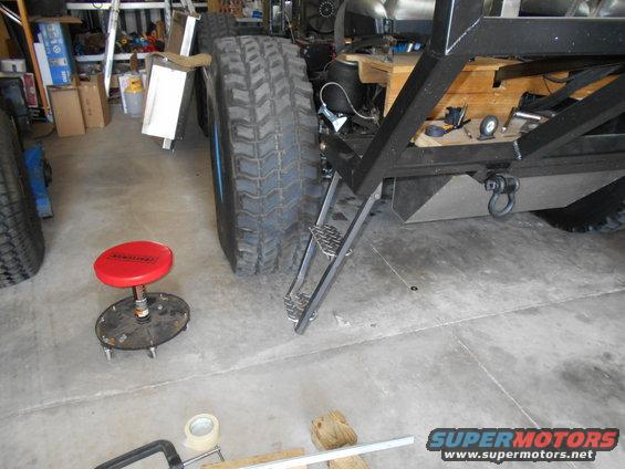 Truck chassis with large tires, metal steps, and a tow hitch