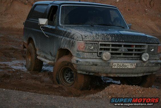 Dark 1987 Ford Bronco stuck in mud, 3q-front view