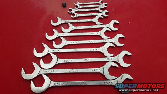 Set of MAC combination wrenches on a red surface, various sizes visible