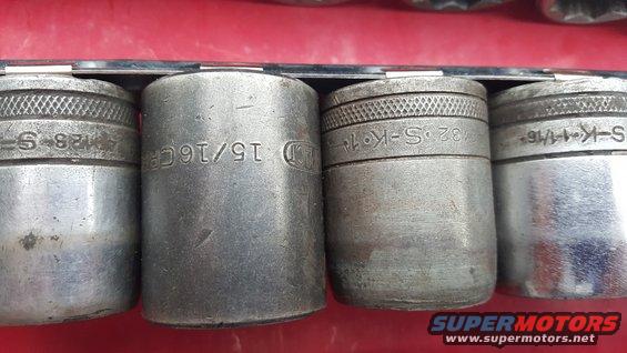 Close-up of four metal sockets in a rack, showing size markings like 15/16