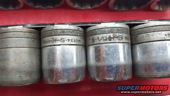 Close-up of several metal sockets with knurled tops and engraved markings
