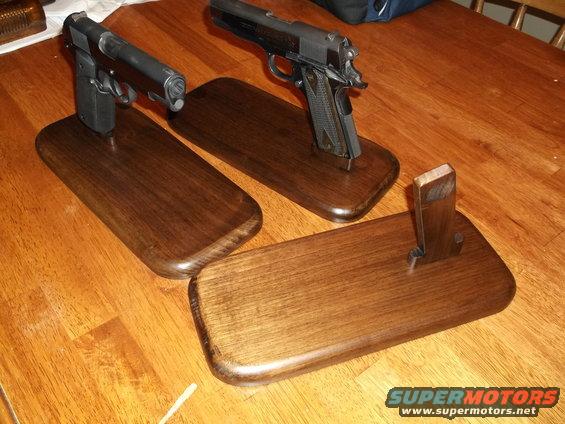 Two handguns on wooden display stands on a wooden table