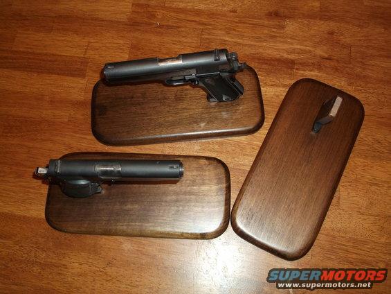 Two handguns displayed on wooden plaques on a wood floor
