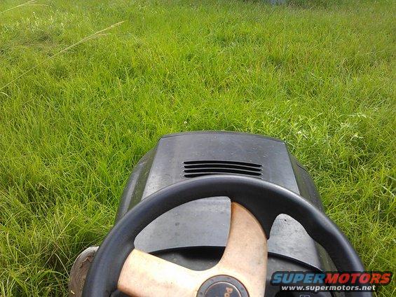 View from the driver's seat of a riding lawn mower, looking out over a grassy field