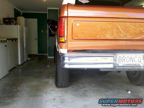 Rear view of an orange Ford Bronco parked in a garage. License plate says BRONCO