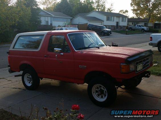 Red 1988 Ford Bronco parked on a driveway, white removable top