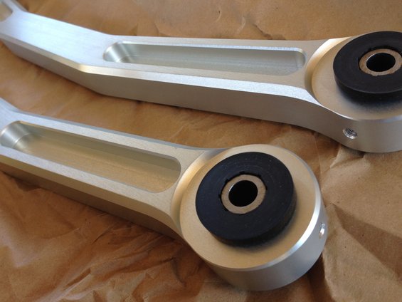 Two silver Metco Watts links with black rubber bushings, laid on brown paper