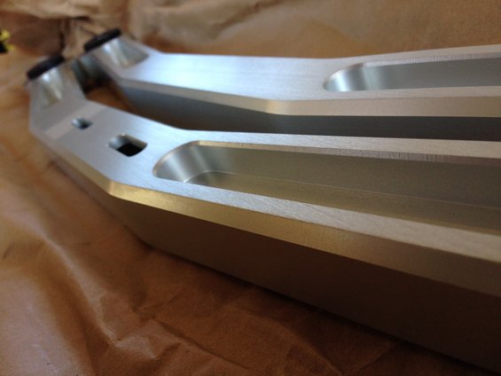 pair of silver aluminum rear suspension control arms with black rubber bushings