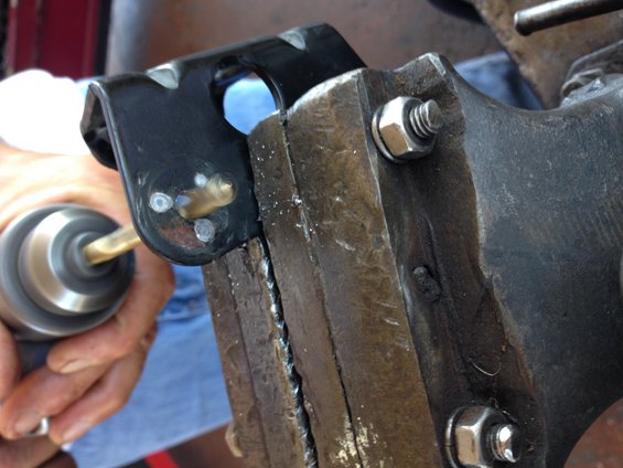 Drilling a black metal bracket held in a vise