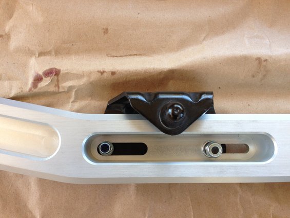 Aluminum suspension part with black bracket and bolts on brown paper