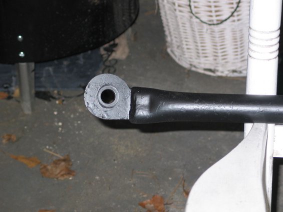 Close-up of a black metal automotive suspension component with a rubber bushing