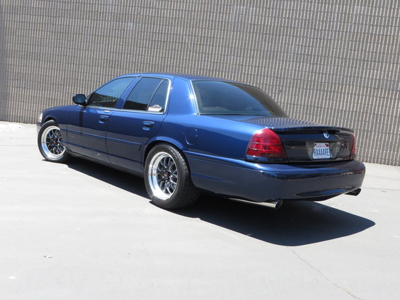 Blue 2003 Mercury Marauder with aftermarket wheels parked in front of a brick wall