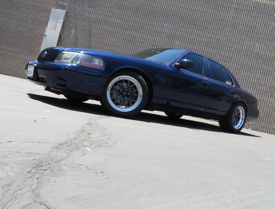 Dark blue 2003 Mercury Marauder with black mesh wheels parked next to a textured wall
