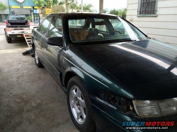 Dark green 1993 Ford Taurus, 3q-front view, missing headlight