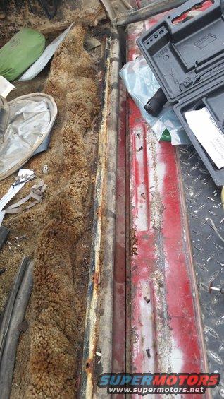 Interior view of worn carpet and red metal panel with tool case