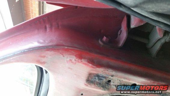 red painted interior of a vehicle's wheel well with some rust and a black cable