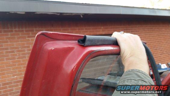 Red vehicle's top edge with weatherstripping being held by a hand