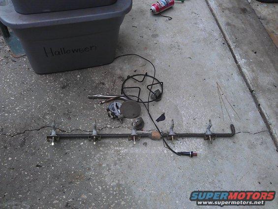 Parts laid out on concrete, including a metal rack with prongs and a grey storage bin labeled 'Halloween'