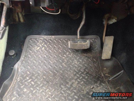 Interior floor of a vehicle with diamond plate floor mat, brake and gas pedals visible