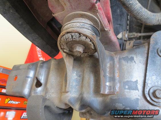 Close-up of a cracked and deteriorated suspension bushing on a vehicle's undercarriage