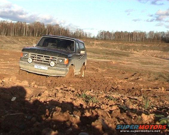 Ford Bronco stuck in a muddy field, front view. License plate visible