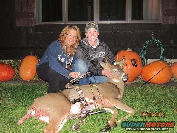 Two women and a deer on grass with pumpkins, date 10/30/2015 visible