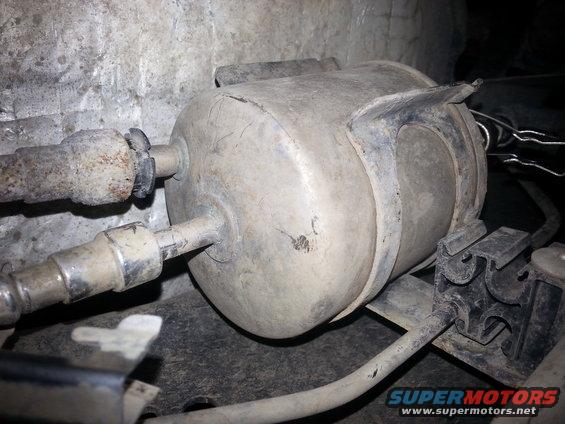 Fuel filter with two hoses attached, mounted to a textured wall