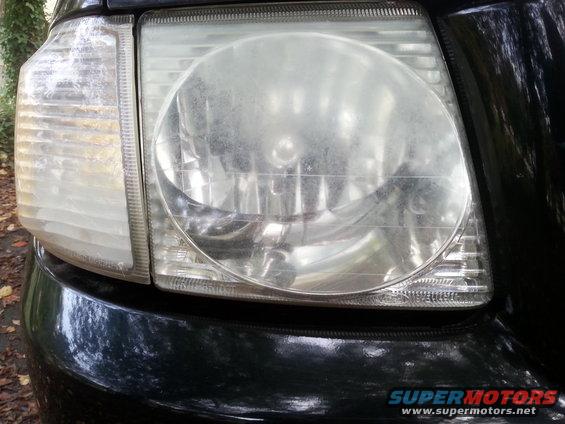 Close-up of a dusty headlight assembly on a dark vehicle