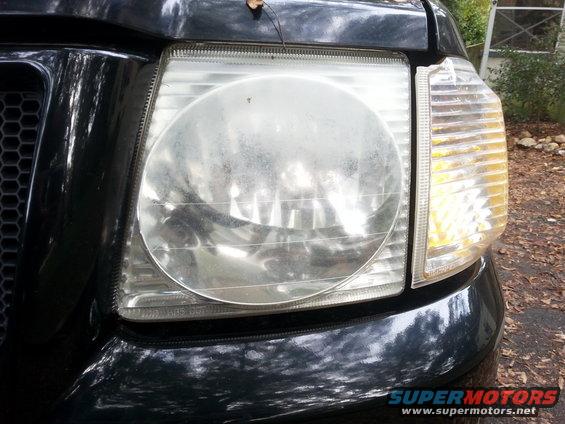 Close-up of a 2001 Ford Explorer's front headlight and grille. The headlight lens is dusty