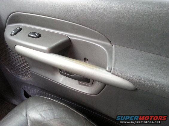 Interior door panel with power window controls and a silver pull handle. The seat is visible in the foreground