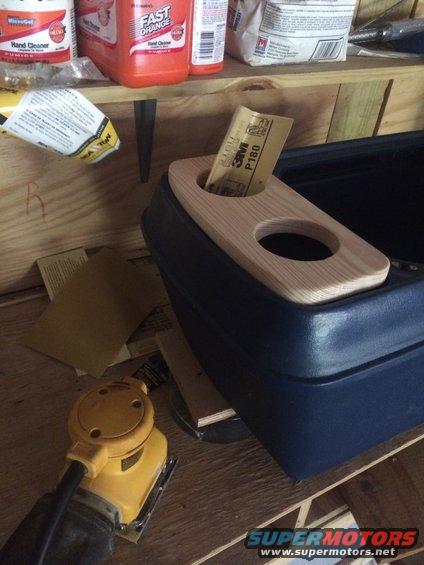 Use a palm sander to get it just right.  It needs to fit down in the grooves around the existing cupholders.   I fastened it (much later) with 2 long brass machine bolts by drilling through the wood and through the plastic.  