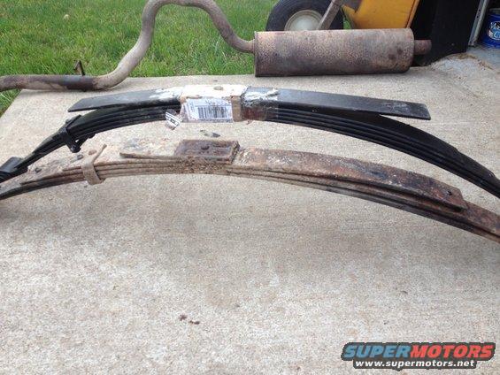 Two leaf springs and an exhaust pipe laid out on concrete