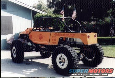 Orange custom buggy with large tires and roll cage, two American flags on poles
