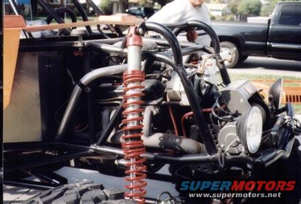 Custom off-road buggy with exposed engine and red coilover suspension