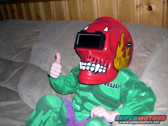 Child in Hulk costume and skull welding mask gives thumbs up