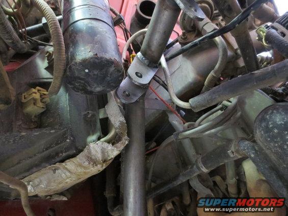 Engine compartment showing hoses, wires, and a custom metal bracket welded onto a pipe