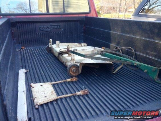 Truck bed with a mower deck and some metal parts loaded