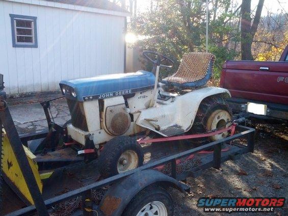 White and blue John Deere tractor with a woven seat cover on a trailer