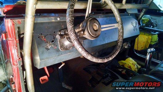 Interior of a modified vehicle with a roll cage, custom dashboard with skull and piston cutouts, and a worn steering wheel