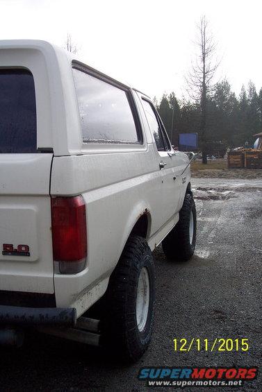 White 1990 Ford Bronco rear quarter panel with 5.0 badge, lifted suspension, and off-road tires