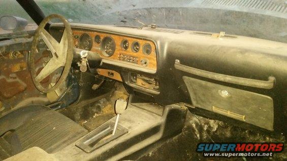1970 Pontiac Firebird interior, dusty dashboard with woodgrain trim, four-spoke steering wheel, automatic shifter
