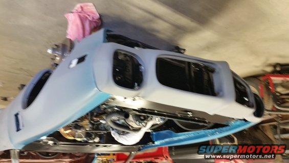 car body on lift, front end disassembled, engine visible