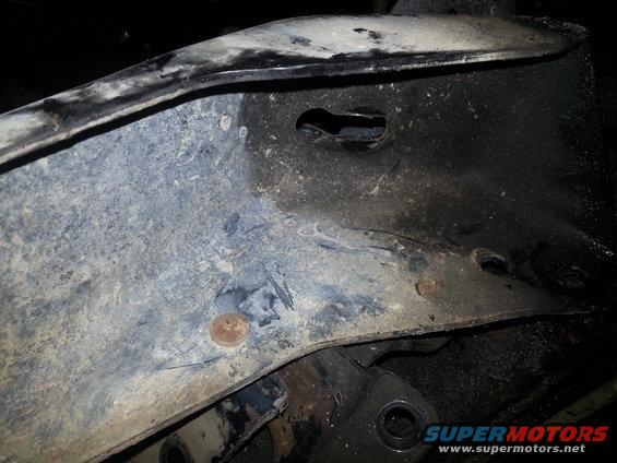 Close-up of vehicle frame with rust spots and holes