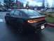 2015 Dodge Dart - The rear of a black Dodge Dart sedan is visible, with its distinctive LED taillights illuminated.