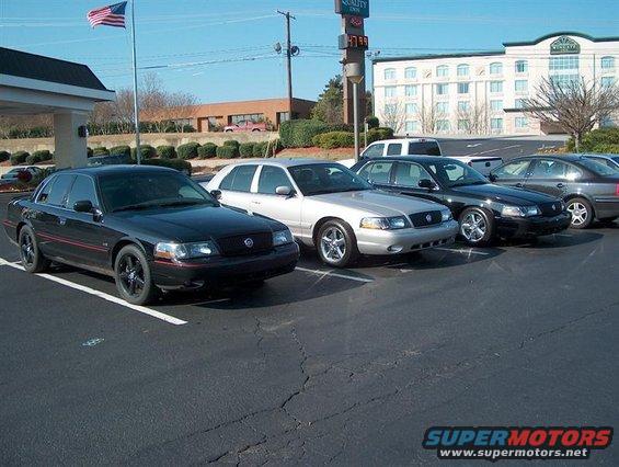 Black 2001 Ford Crown Victoria with red trim and black wheels parked in a lot