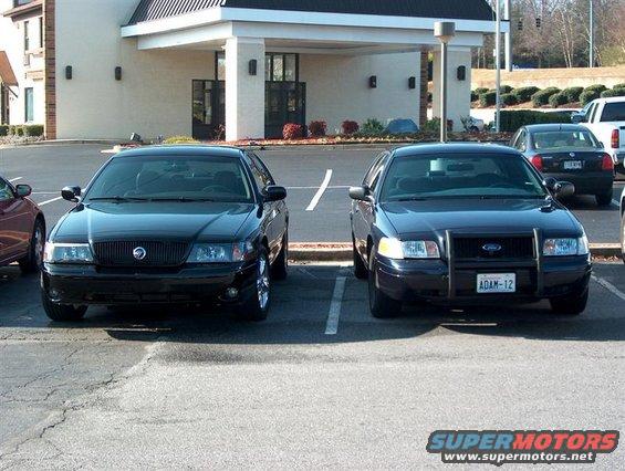 Black Mercury Grand Marquis and a dark blue Ford Crown Victoria police car parked side-by-side