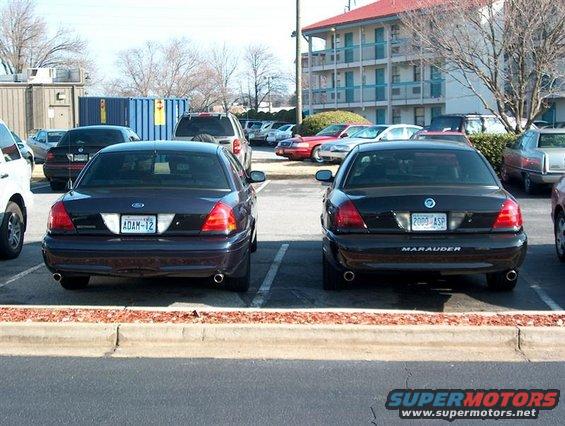 Two Ford sedans parked in a lot; one is a dark Marauder, the other is a dark Crown Victoria