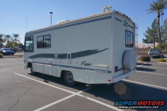 White RV with a dark stripe and 'Flair' text, parked in a lot