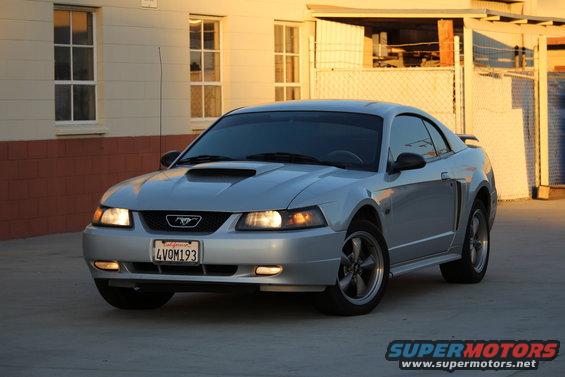 Silver 2002 Ford Mustang coupe with a hood scoop and aftermarket wheels parked outdoors