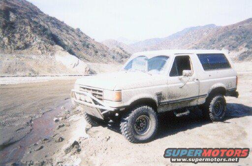 White Ford Bronco with aftermarket bumper parked on a dirt road
